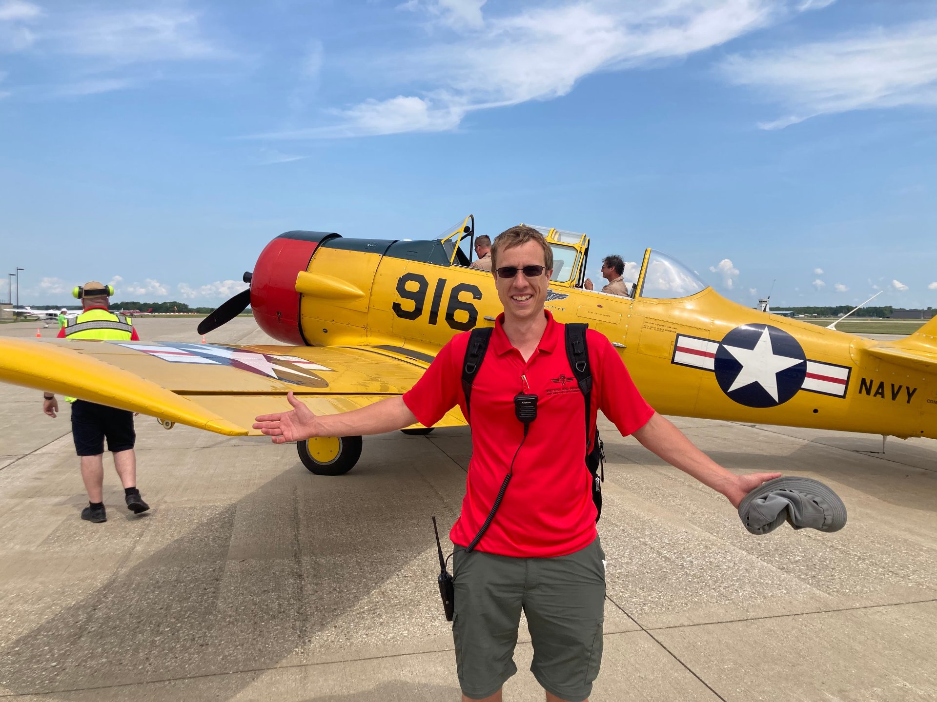 A man smiling while standing in front of an SNJ on a runway