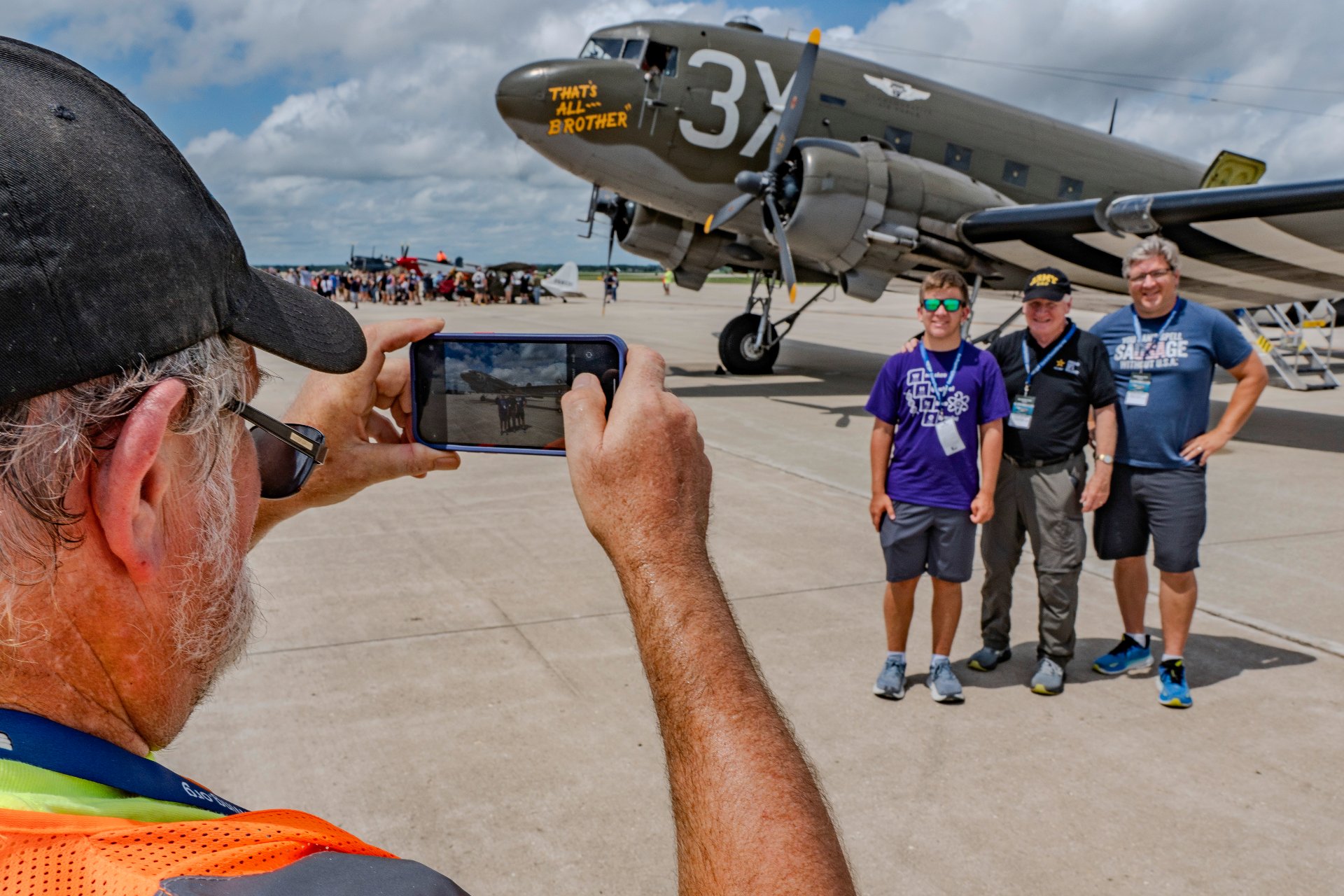 Visitors pose for a photo in front of the World War II aircraft That's All, Brother on the tarmac