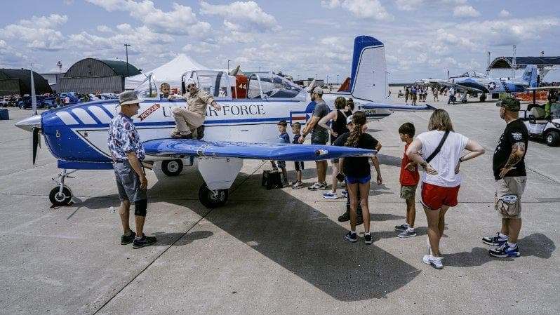 A crowd of people looking at a T-34 parked on the runway