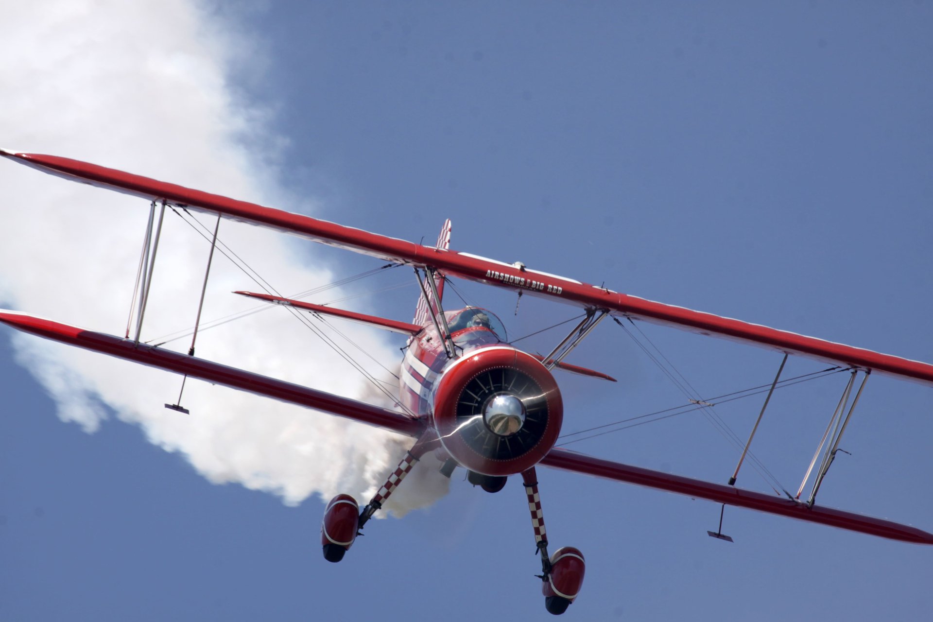 Biplane flying in the air with a trail of smoke behind it
