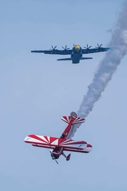 Biplane flying in front of a larger aircraft
