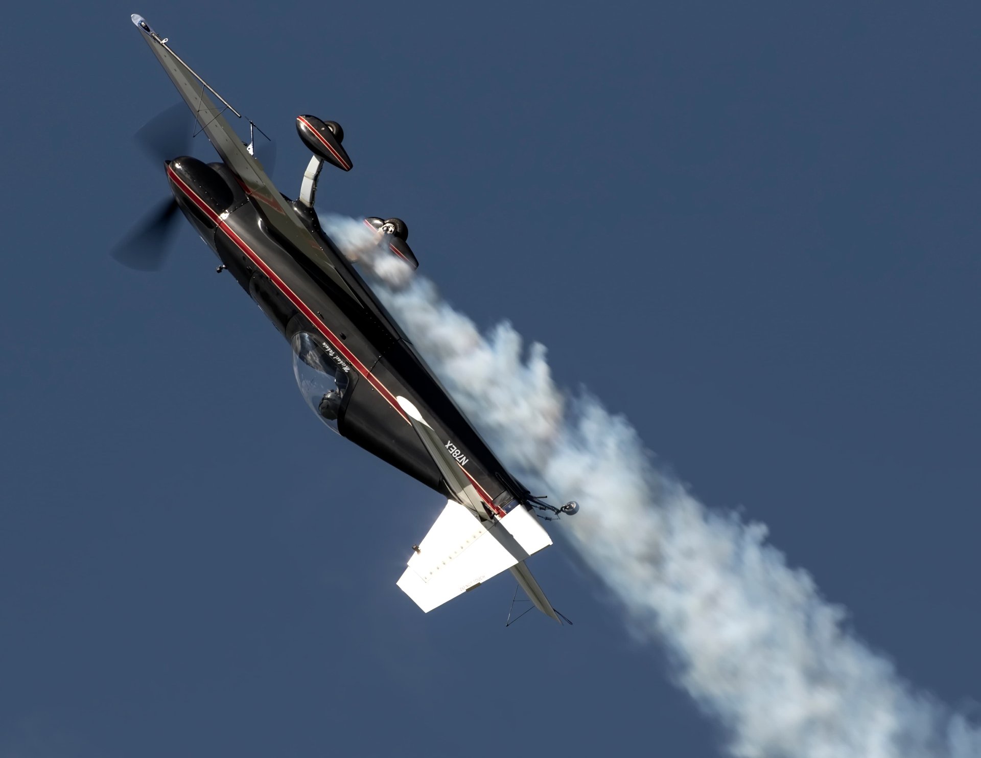 Extra 300L flying upside down with smoke trailing behind it