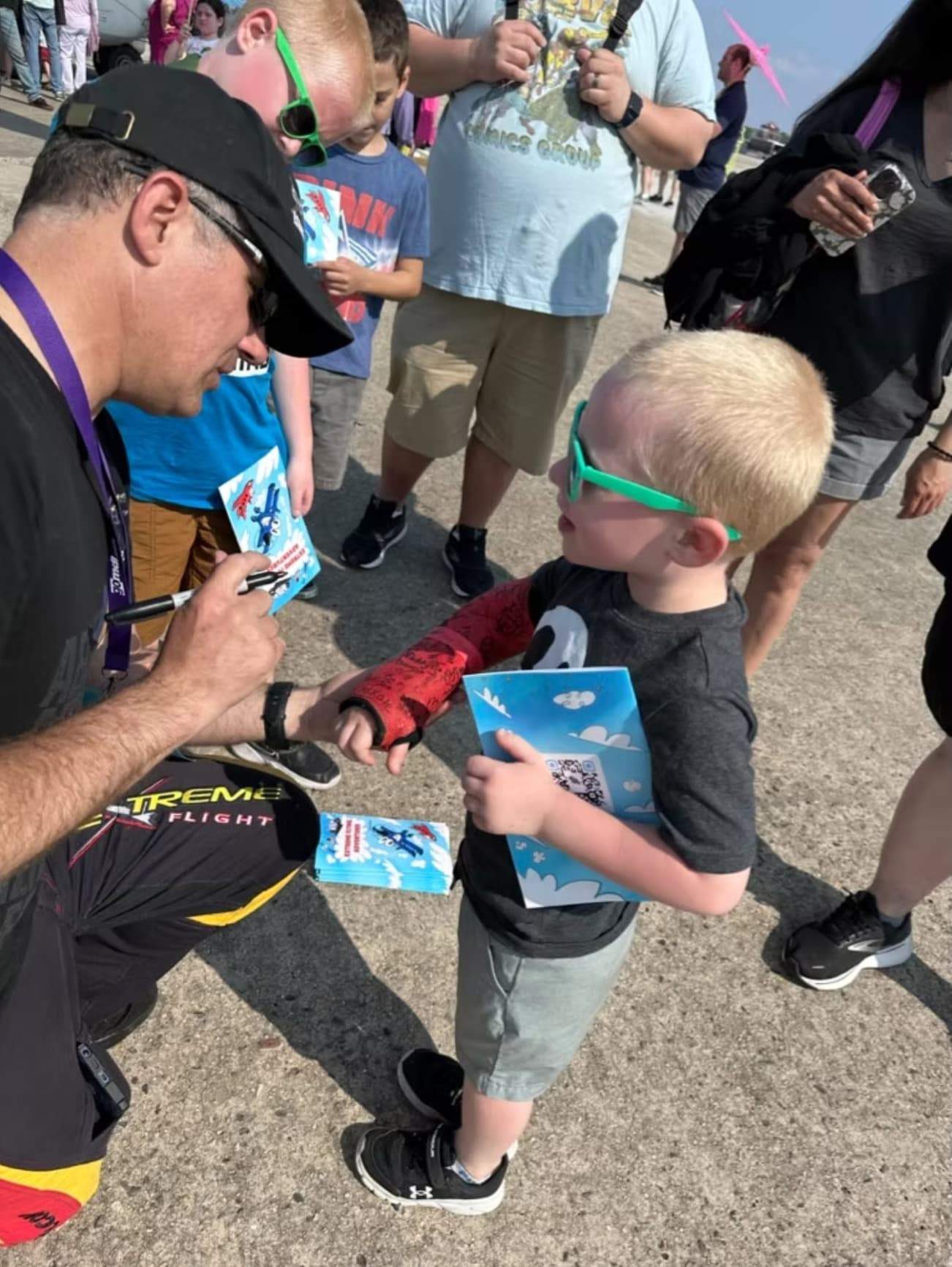 Airshow pilot signing a book for a young fan during a meet-and-greet at an airshow.