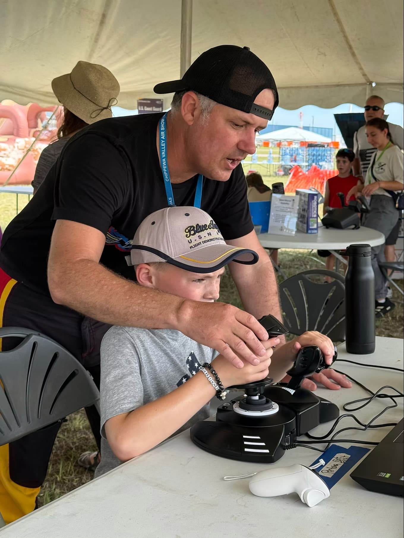 Pilot helping a child operate flight simulator controls during an aviation education activity.