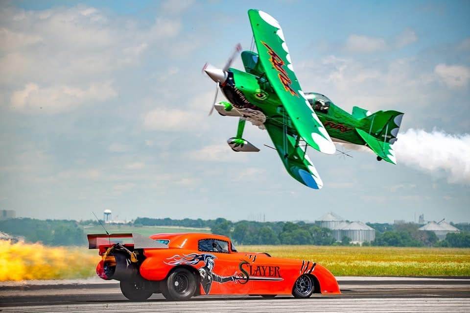 Slayer Jet Car racing on a runway with a stunt plane flying overhead