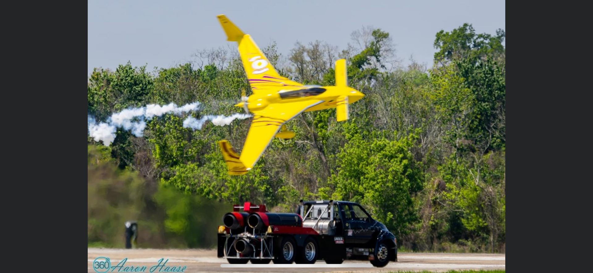 Jet truck on the runway with a yellow aircraft flying overhead