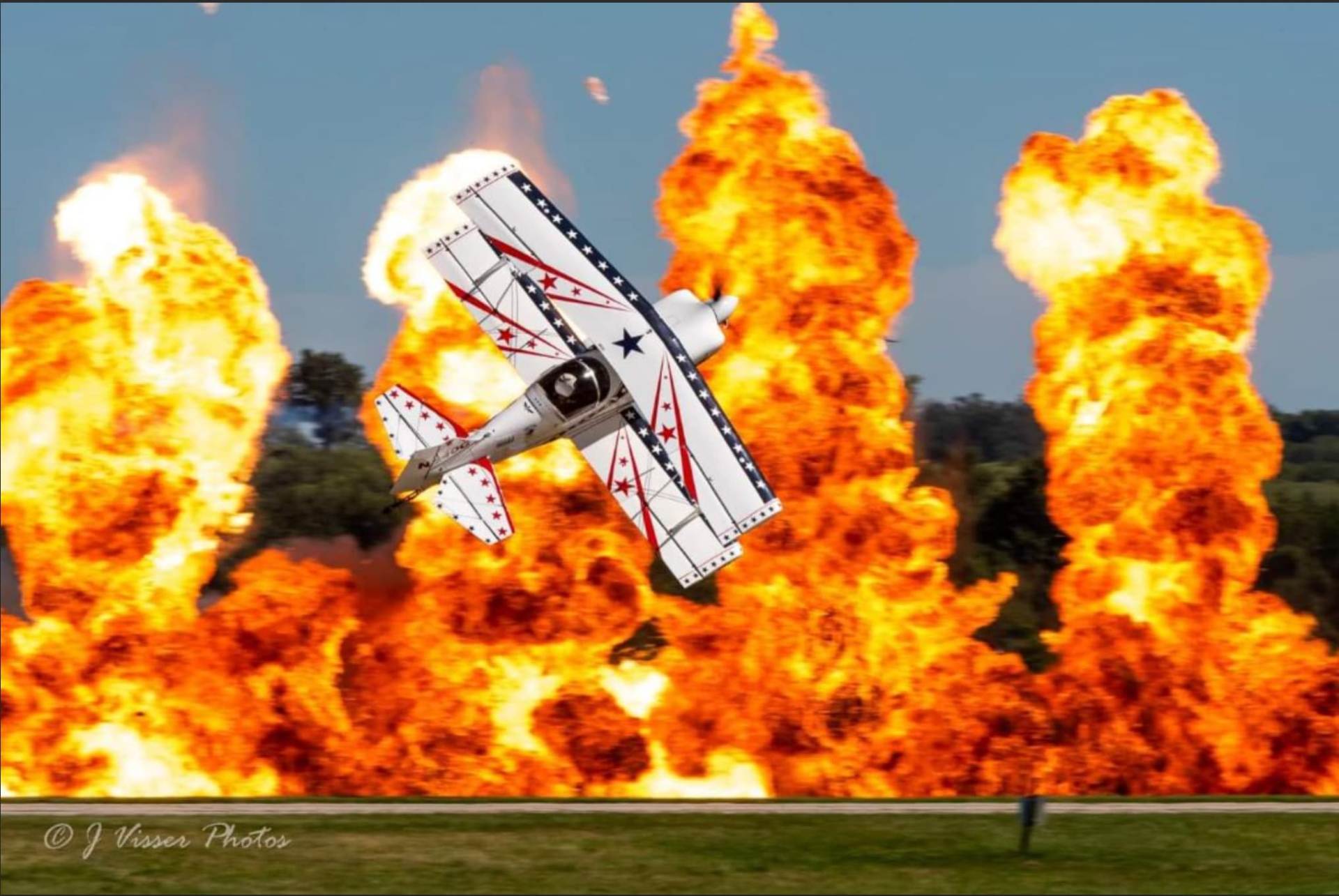 Machaira biplane flying past a wall of fire