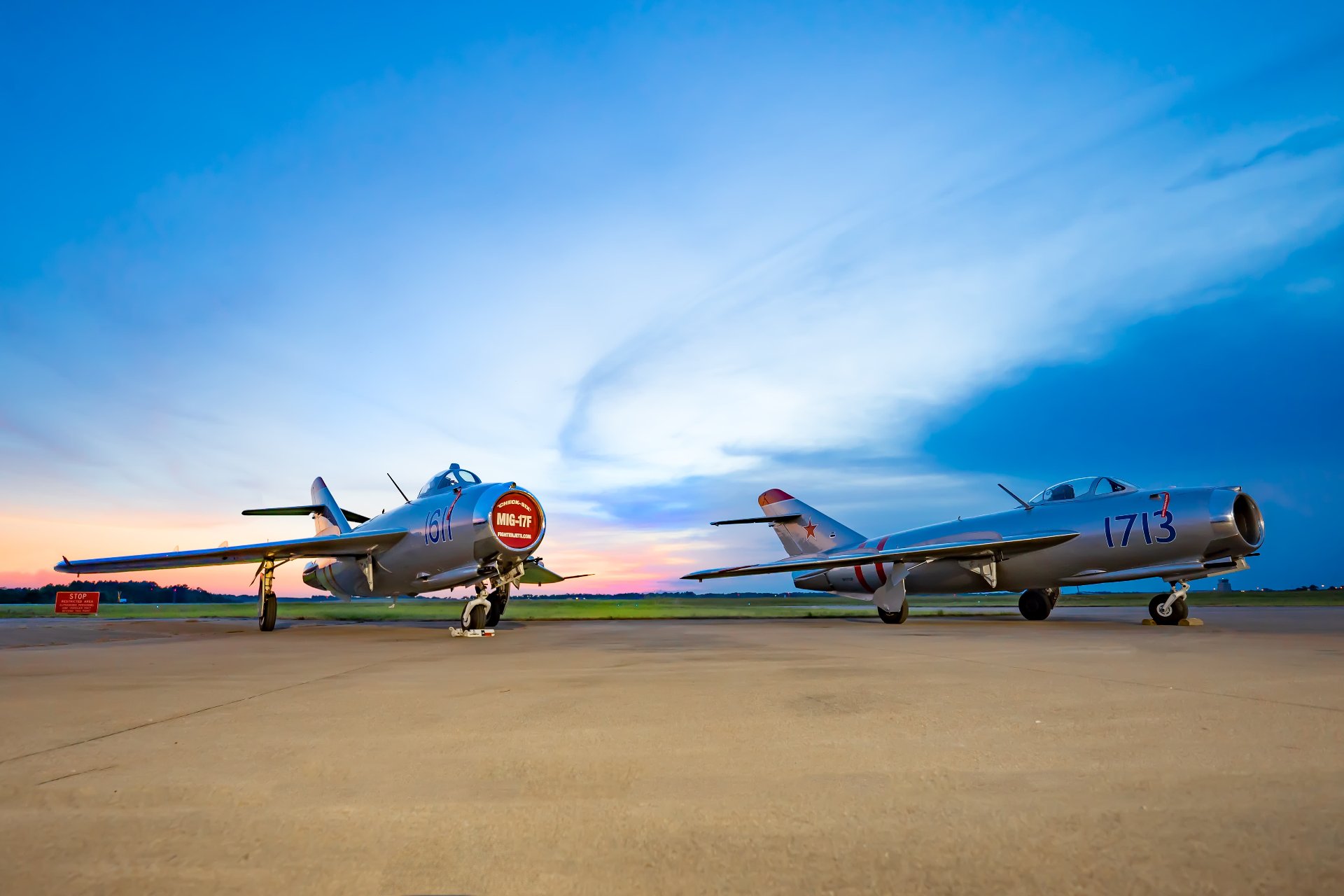 Two MiG-17F jets on the ramp at sunset.