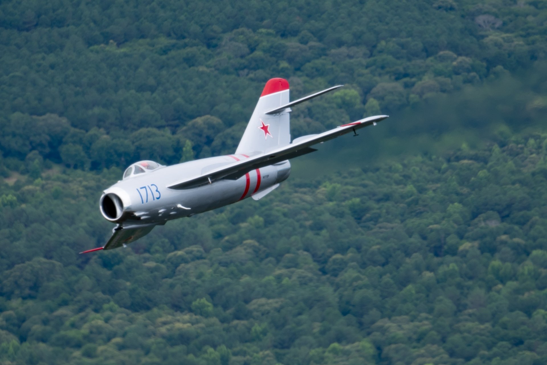 MiG-17F Jet banking right over a forest.