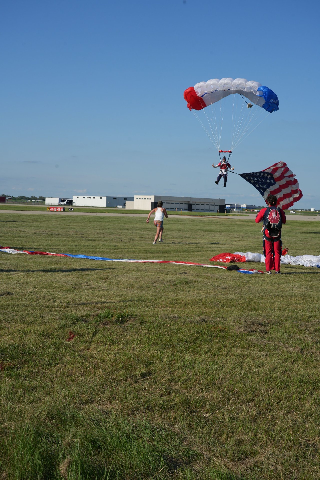 Skydiver about to land with an American flag behind him
