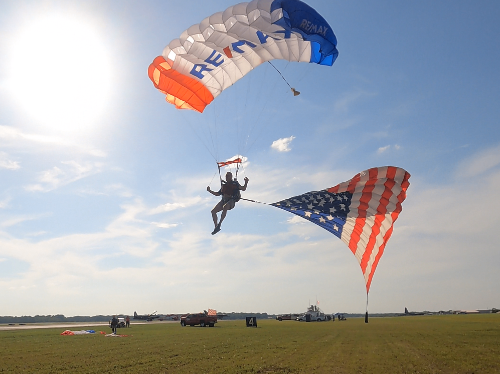 RE/MAX skydiver above a farm field, about to land