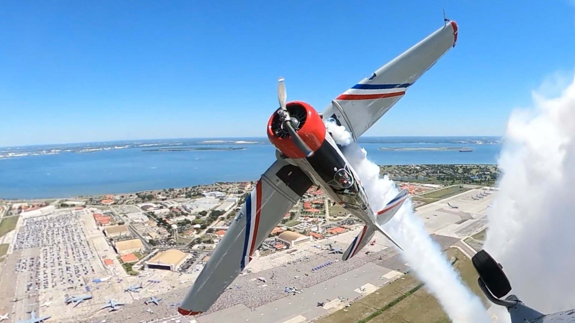Warbird Thunder SNJ Texan banking over the airshow with a white smoke trail.