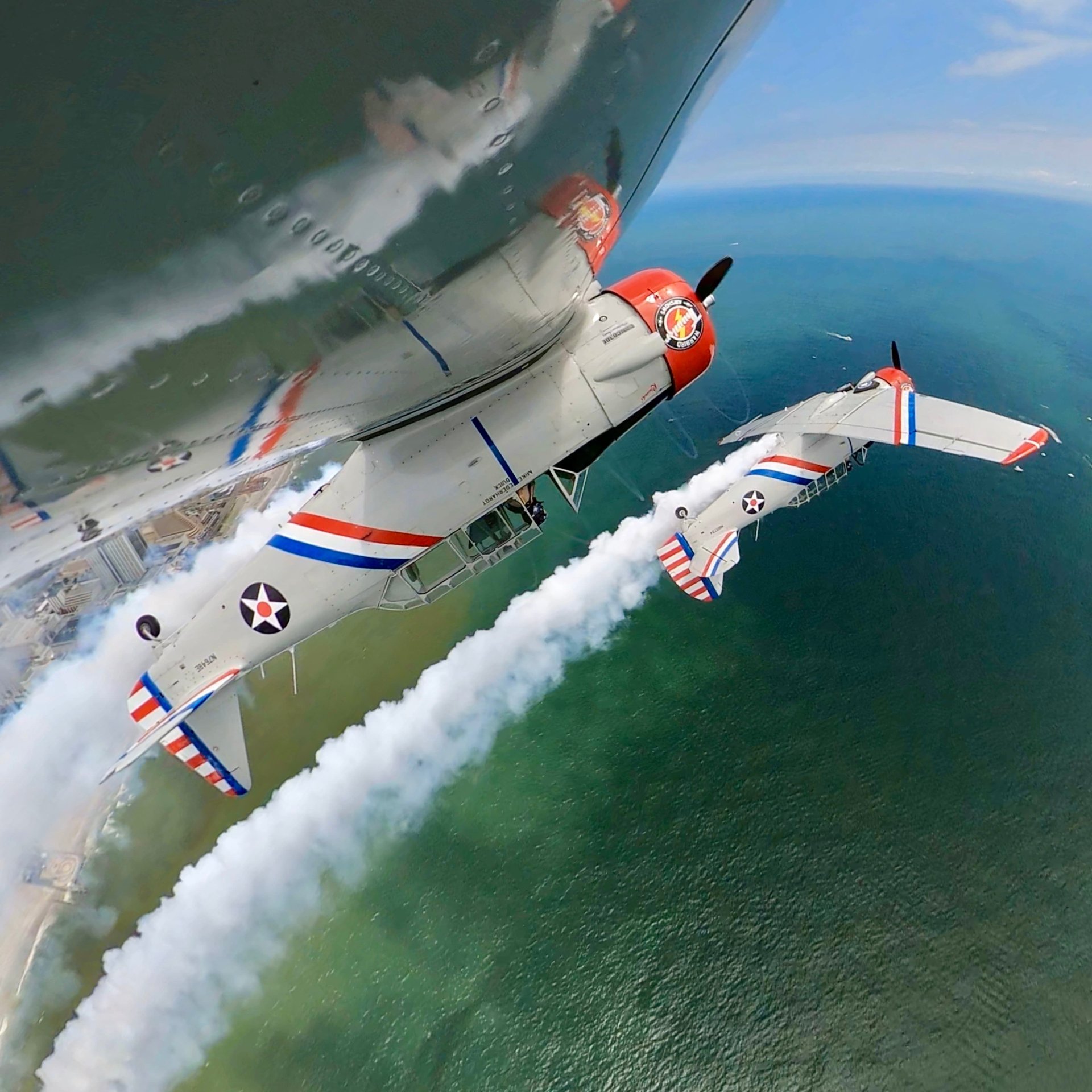 Warbird Thunder SNJ Texans in formation with smoke trails over the sea.
