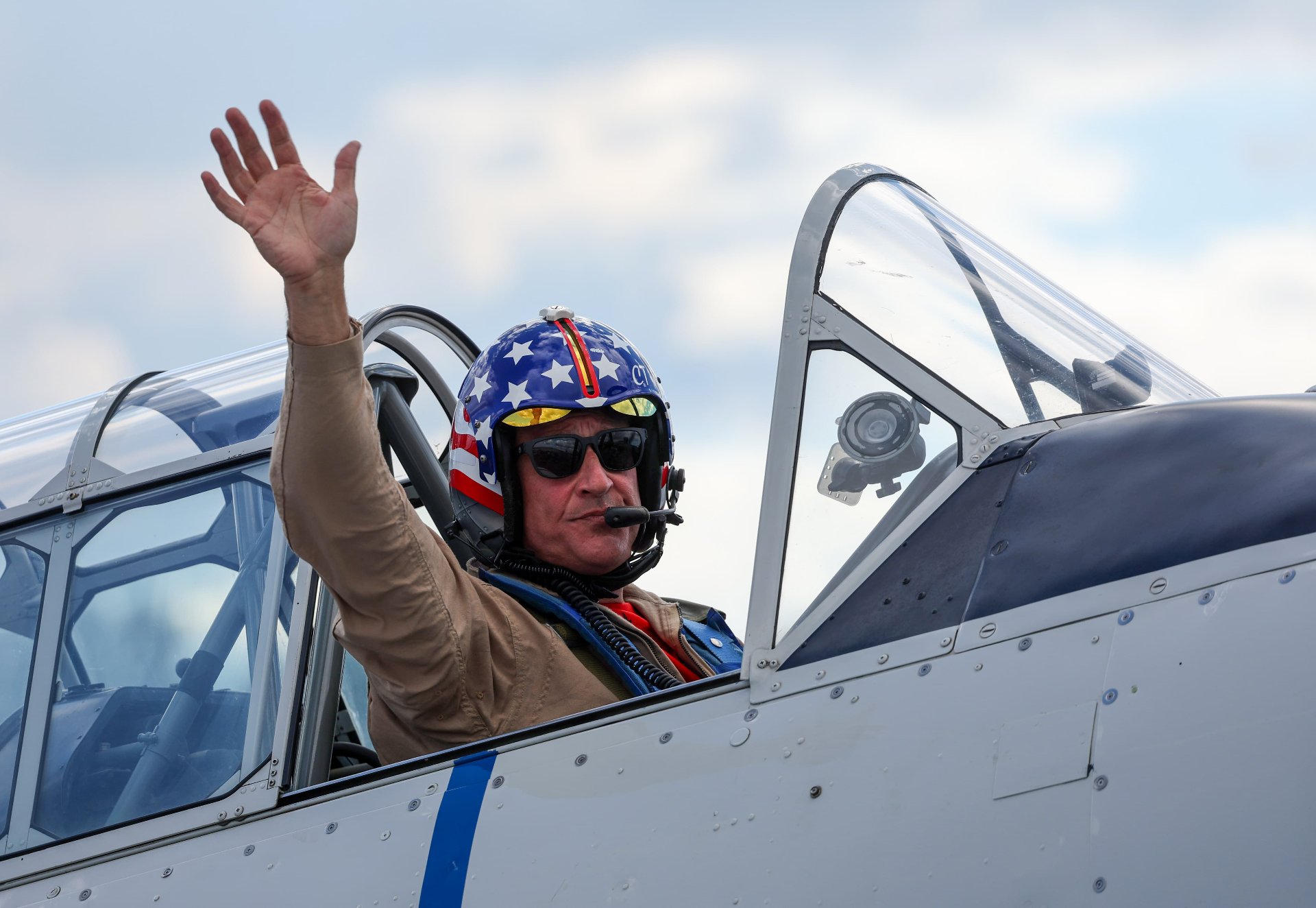 Chris "CT" Thomas in a flight suit waving from the cockpit of an SNJ Texan during a performance.