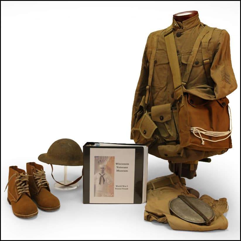 World War I military uniform and field gear displayed with jacket, boots, helmet, satchel, canteen, blanket roll, and travel trunk binder.